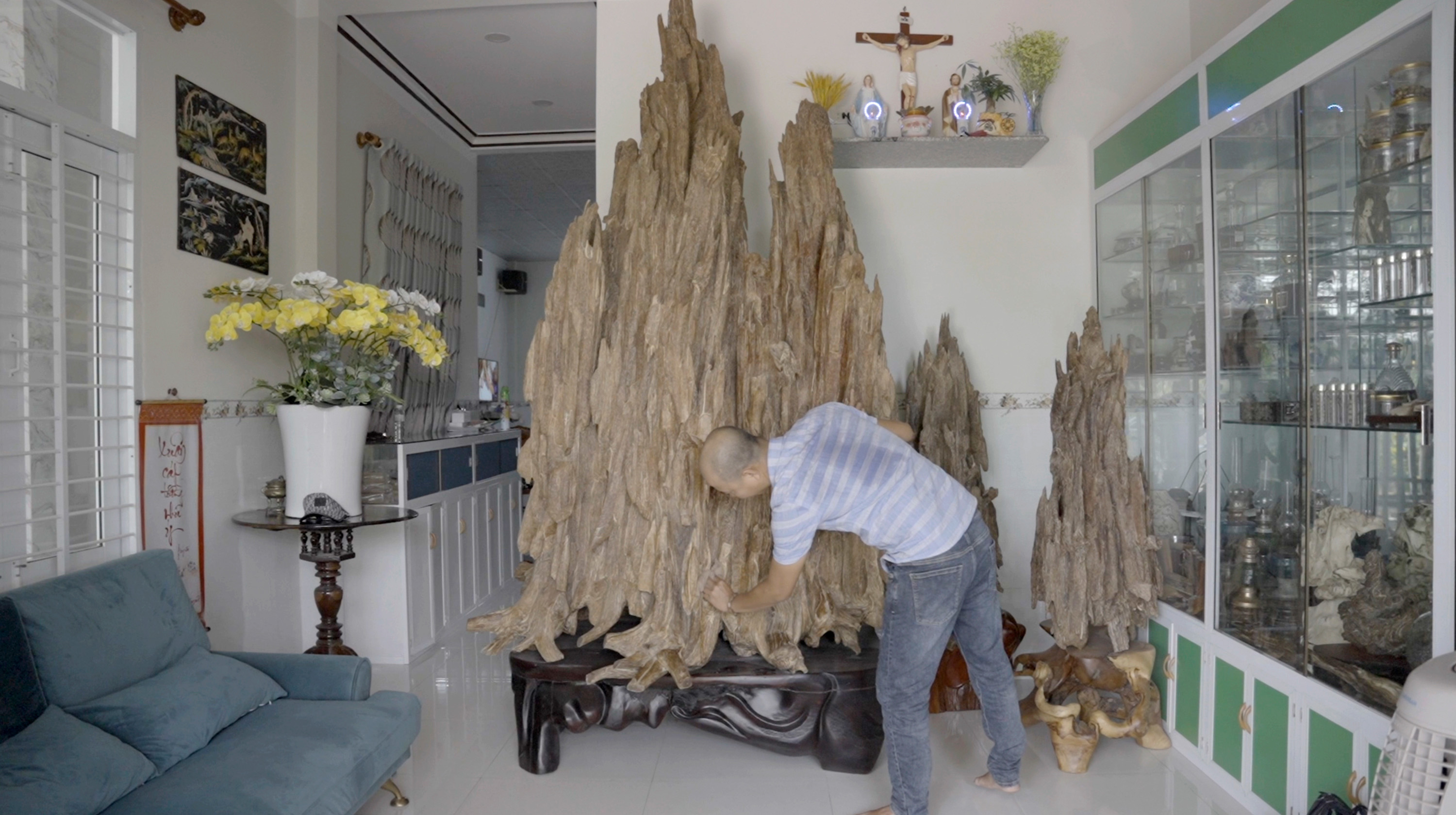 An Agarwood dealer and collector is taking care of his Agarwood sculpture. The Agarwood is supposed to protect its owner from bad spirits. It is also considered as a status and wealth symbol. Still from the documentation film from „Scent from Heaven“. 2023