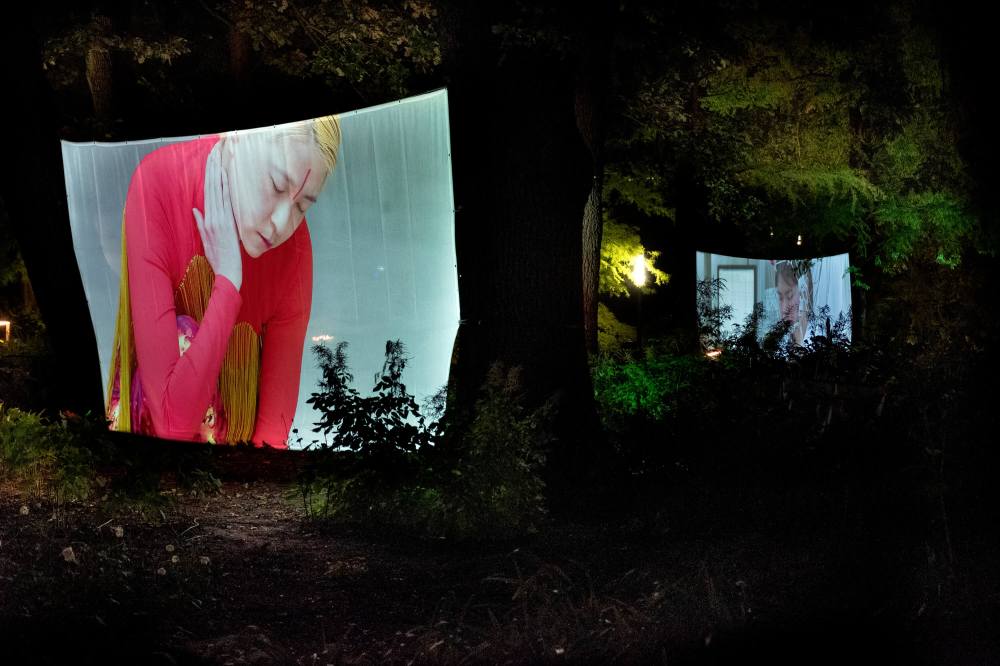 Installation at Planten un Blomen park in Hamburg by Hiền Hoàng, featuring large-scale video projections on towering trees. The immersive experience comprises three distinct screens, each showcasing a different film from the 'Scent from Heaven' project. The videos explore themes of tree’s suffering, human’s dream of healing and salvation and sensory perception, enveloping viewers in a mesmerizing blend of sight and sound amidst the natural surroundings of the park.