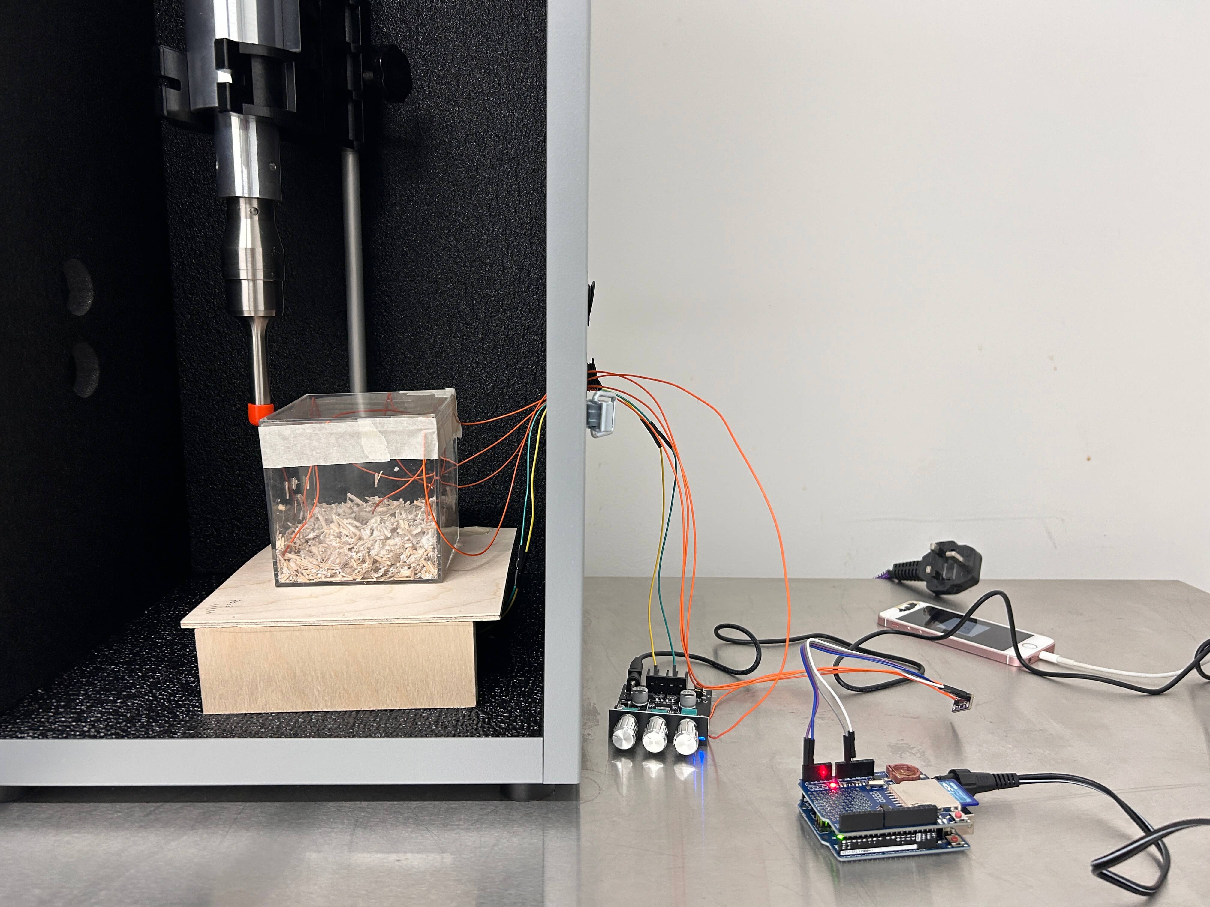 Prototyping Violence. Mycelium Resonance Study. Measurement of mycelium’s electrical signal while being exposed to the vibratified acceleration data of a tree: Mycelim, Arduino, ADS board, wooden board with shaking device mounted underneath, amplifier, iphone. 2025